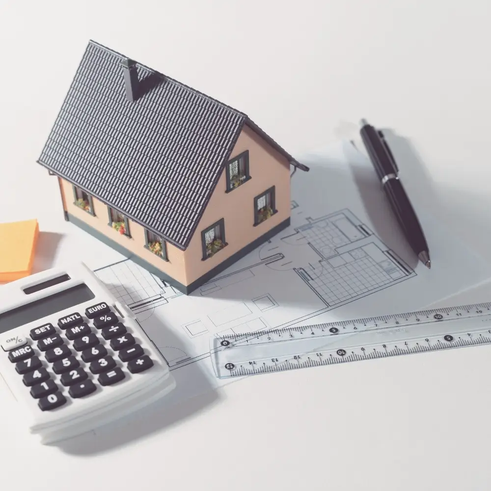 Model house, floor plan, and calculator on a white surface, representing home planning and purchase home loans.