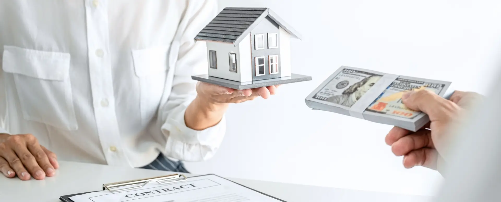 Person holding a house model, another handing cash, with a contract—symbolizing a real estate deal with a mortgage lender.