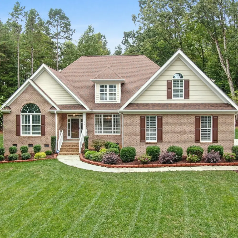 Brick house with gabled roof, manicured lawn, and walkway—ideal for first-time home buyers or those seeking mortgage refinance.
