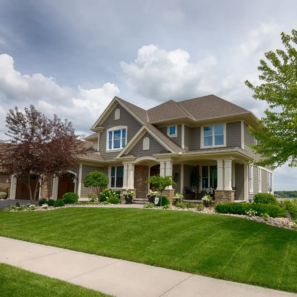 Two-story suburban house with gray siding and stone accents, perfect for home loans or mortgage refinance options.
