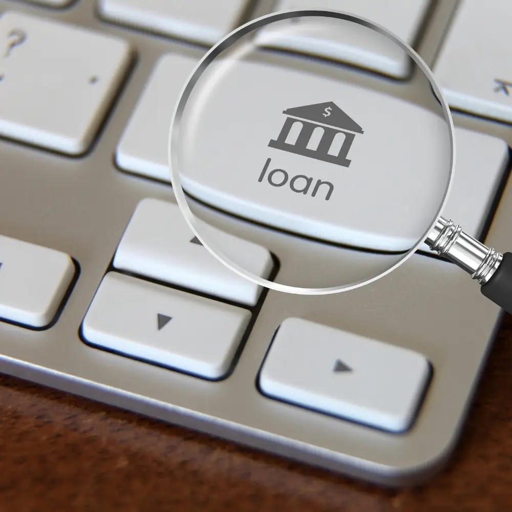 A magnifying glass highlights a keyboard key labeled with a bank icon and "loan" for first-time home buyers.