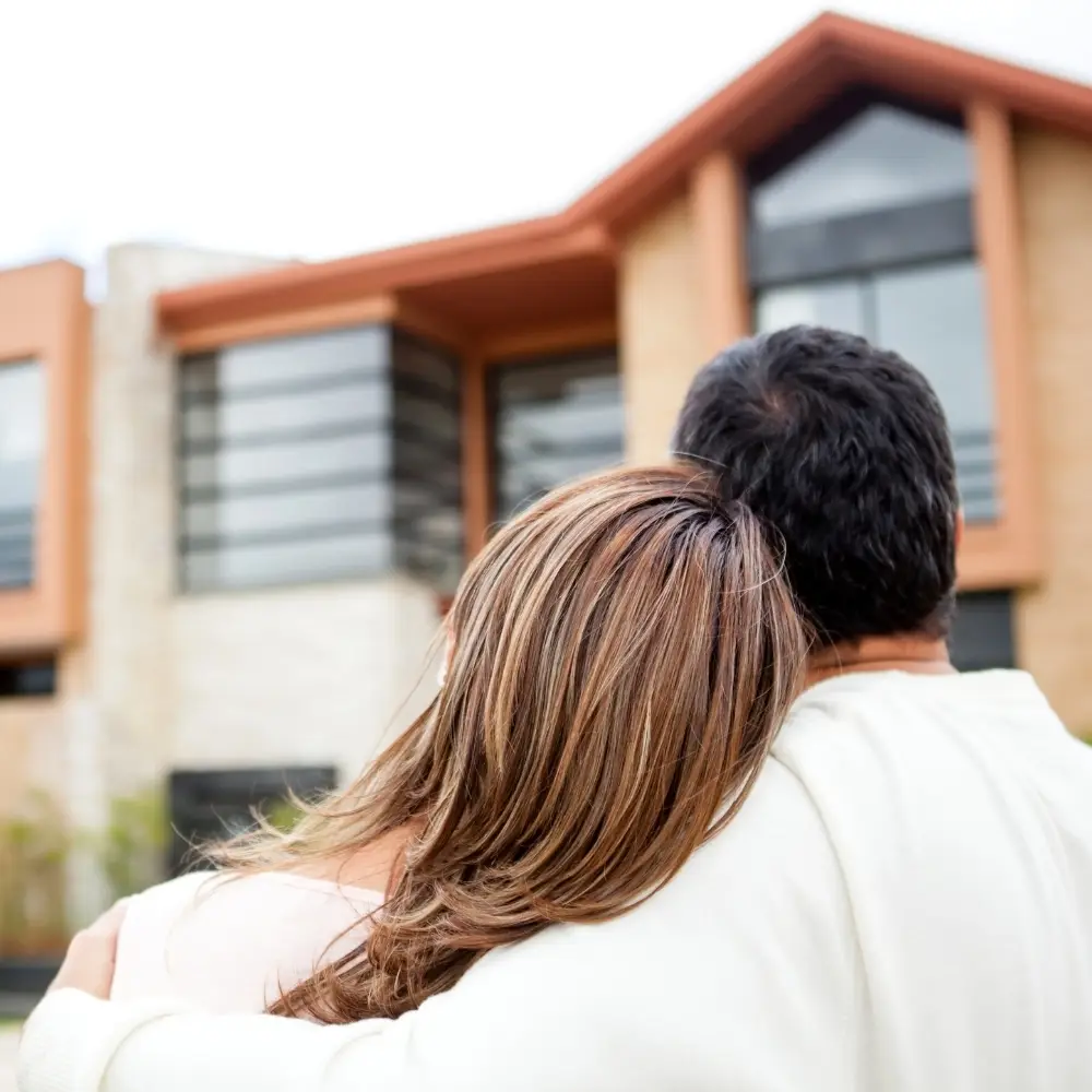 A couple embraces while looking at a modern house—an inspiring scene for first-time home buyers.