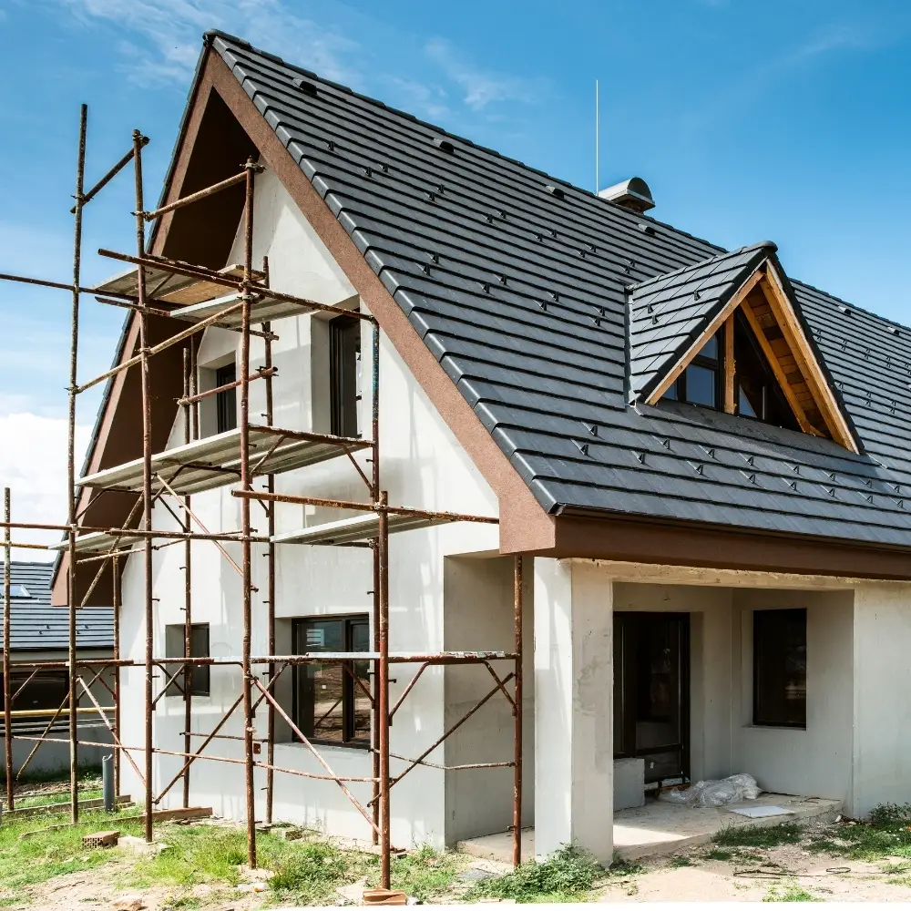 A modern house under construction, ideal for first-time home buyers with available home loans and a steep, dark-tiled roof.