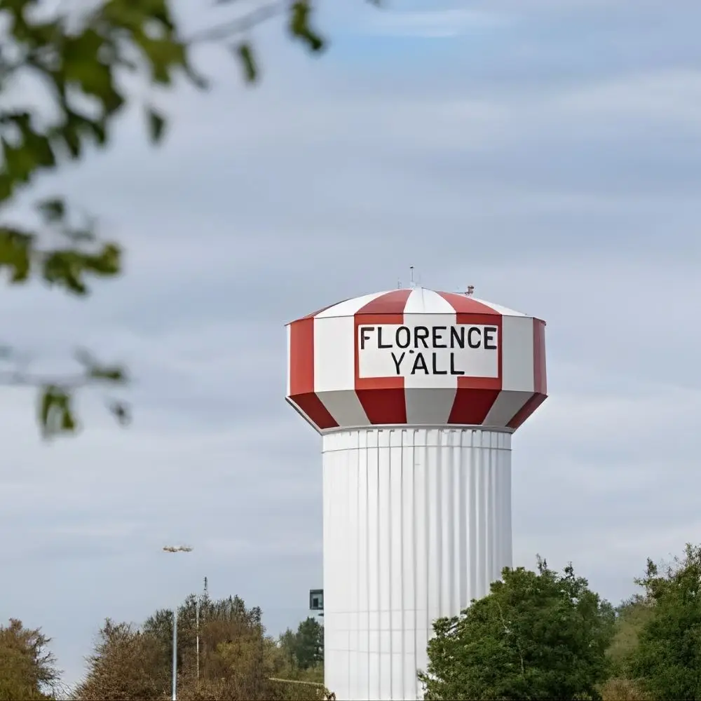 A red and white water tower with FLORENCE YALL stands among trees—iconic above the city’s home loans and neighborhoods.