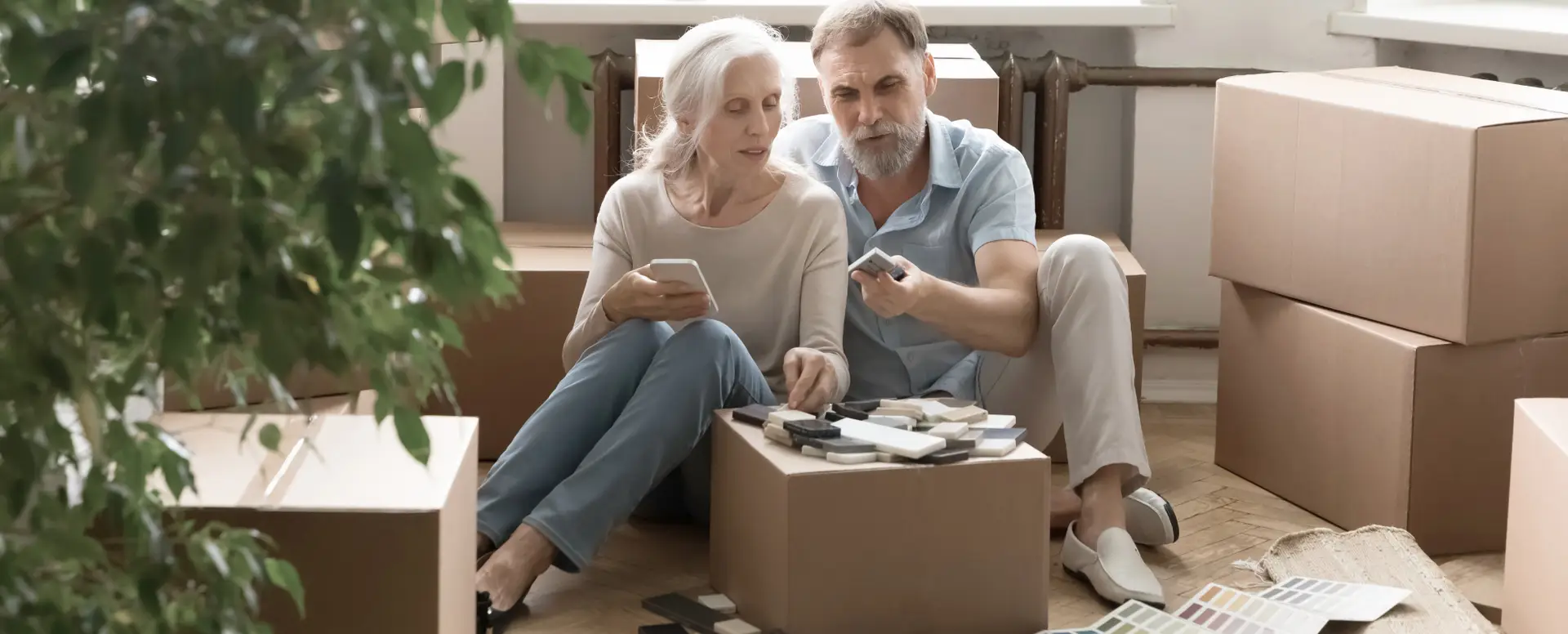 Older couple sits on floor with color samples, planning their new home and discussing purchase home loans.