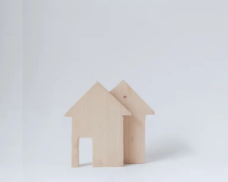 Two simple wooden house models on a light background, perfect for illustrating mortgage lender concepts.