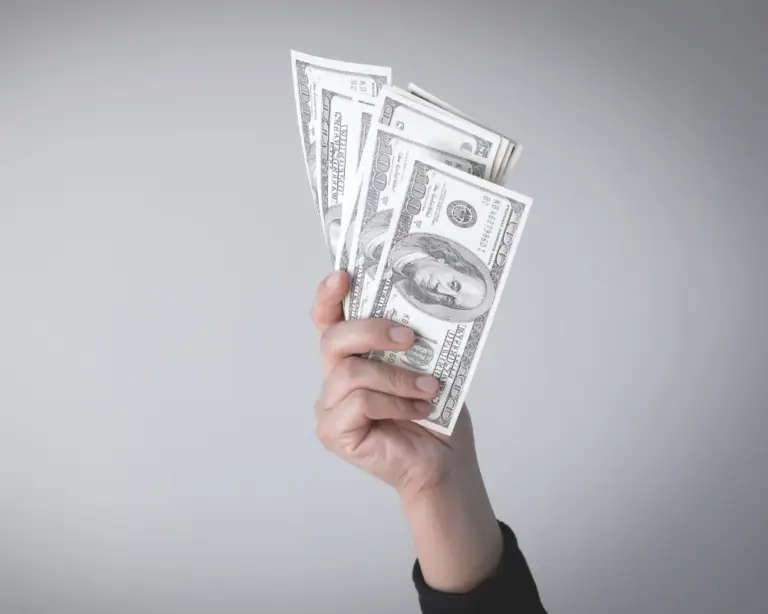 A hand holding fanned-out hundred-dollar bills—ideal for first-time home buyers seeking purchase home loans.