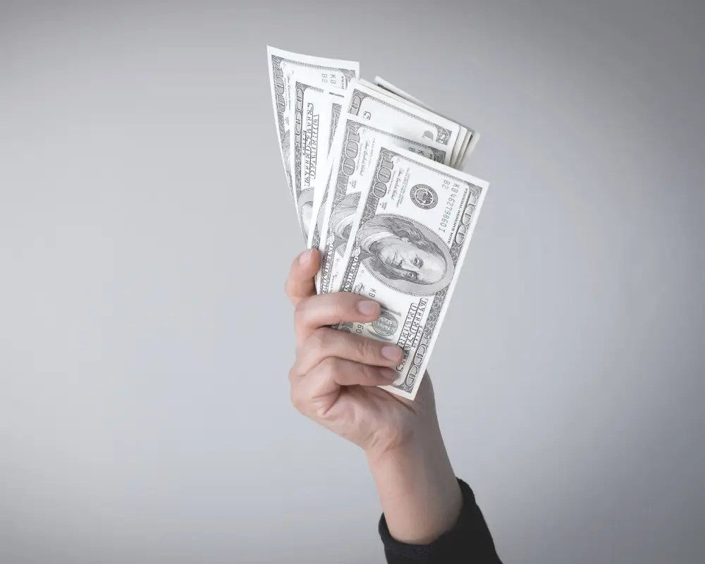 A hand holding fanned-out hundred-dollar bills—ideal for first-time home buyers seeking purchase home loans.