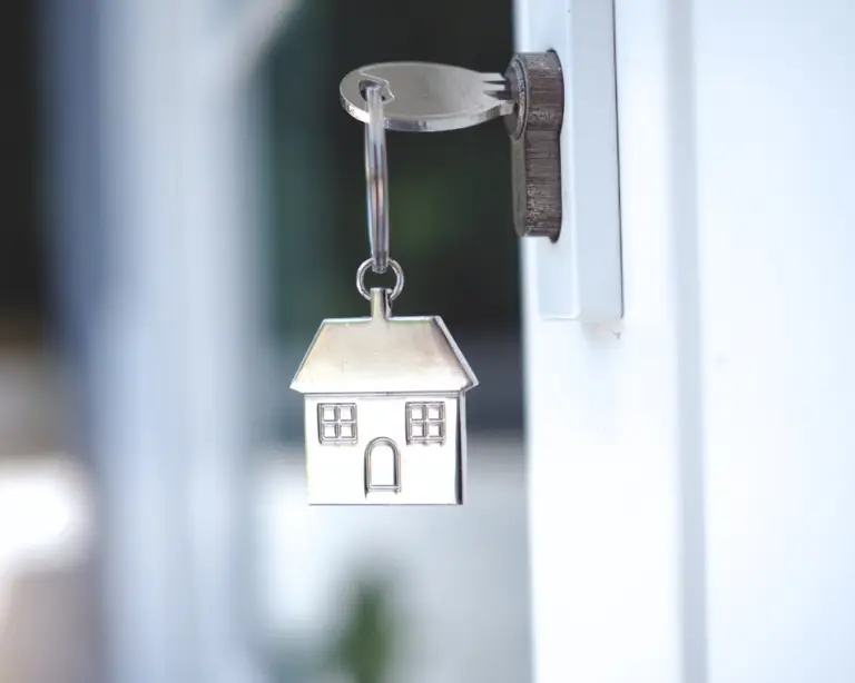 A house-shaped keychain hangs from a key in a door lock, symbolizing new beginnings with home loans.