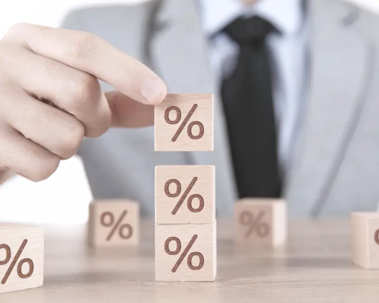 A person in a suit stacking wooden blocks with percentage symbols, symbolizing mortgage refinance options.