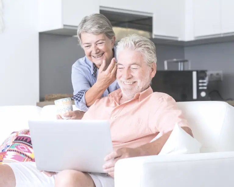 Smiling older couple on a couch, exploring mortgage refinance options together in a bright living room.