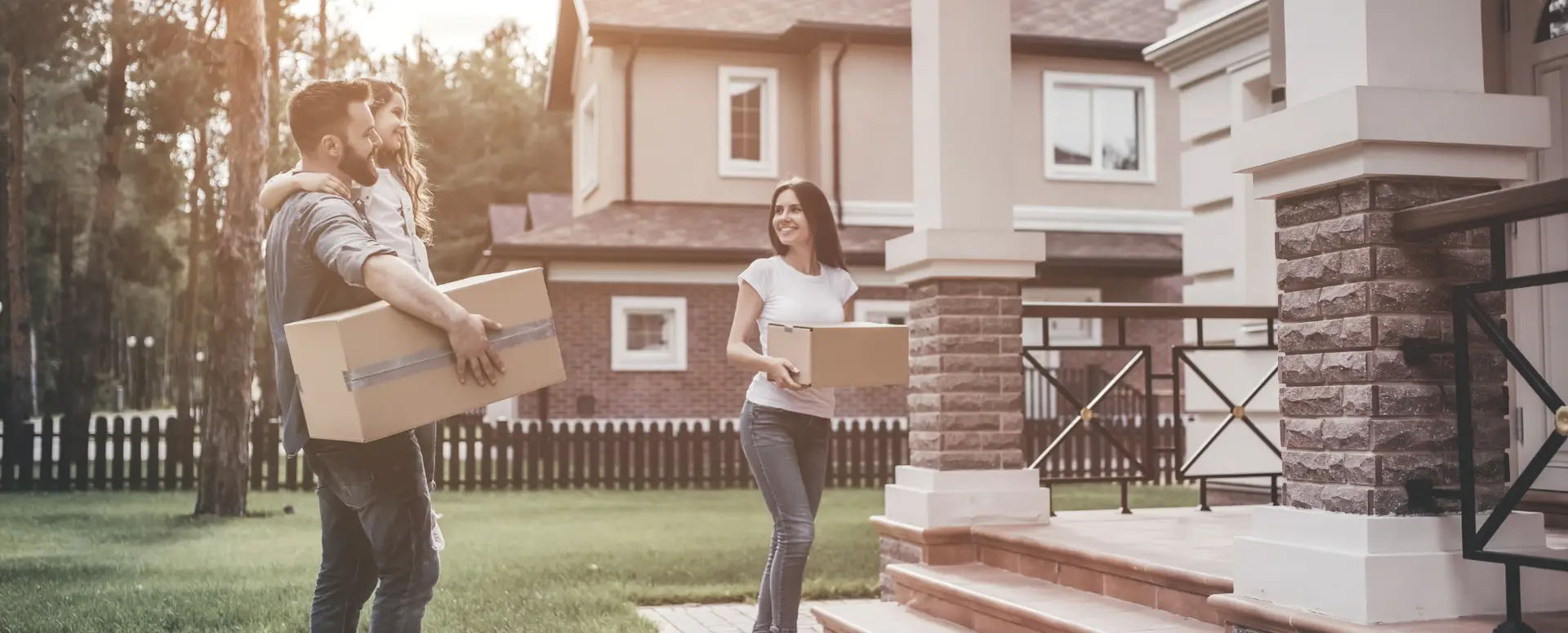 A couple with a child and a woman carry moving boxes, excited for new beginnings with flexible home loans.