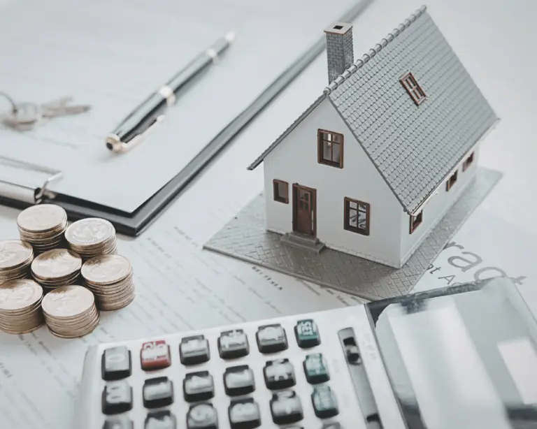 Model house, coins, and paperwork on a desk, representing home loans, mortgage refinance, or real estate planning.