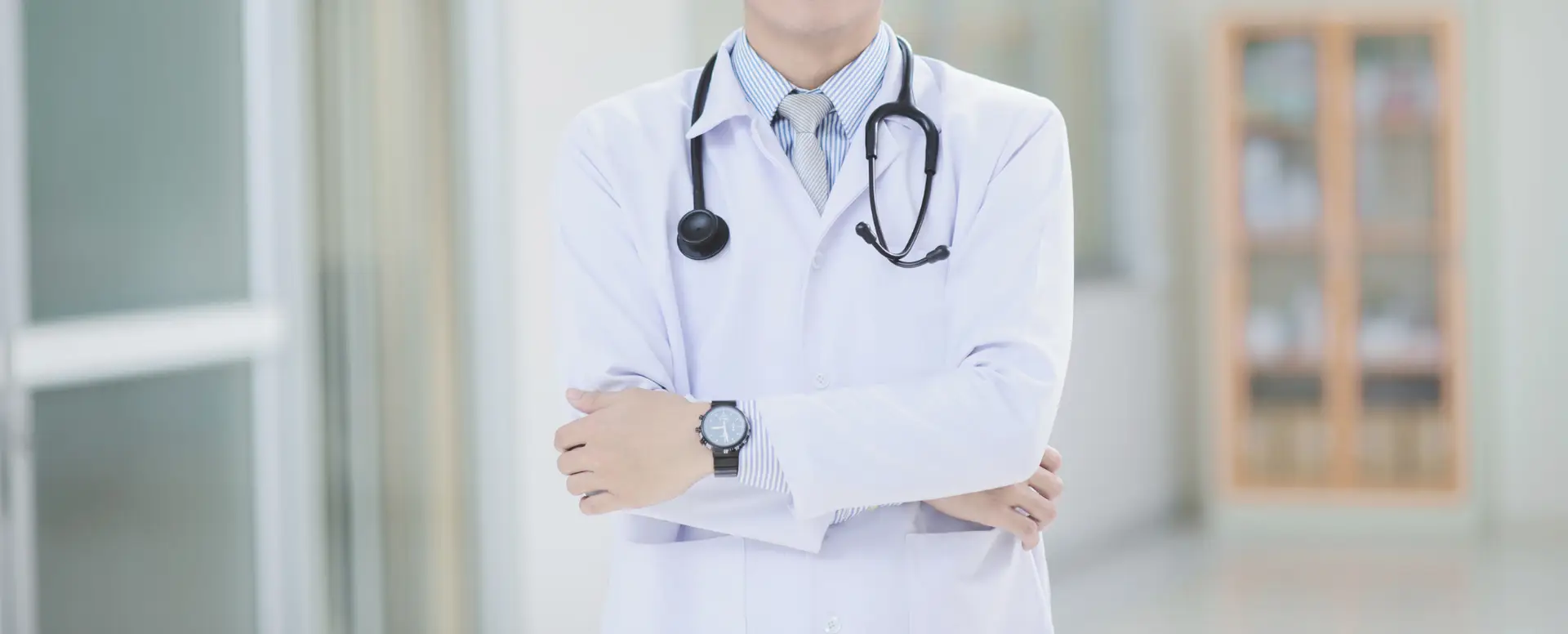 A doctor in a white coat with a stethoscope stands confidently, ready to advise first-time home buyers in a bright hallway.