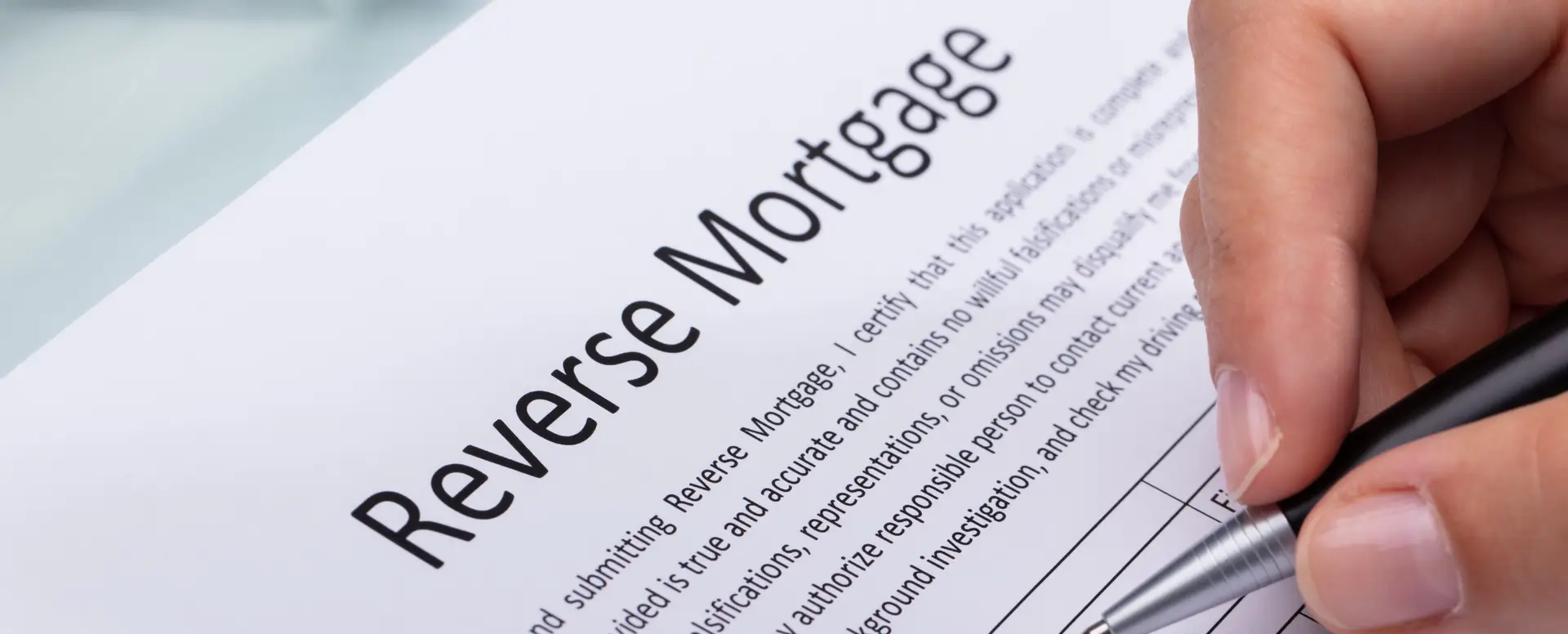 A person fills out a reverse mortgage application form with a pen for their mortgage lender.
