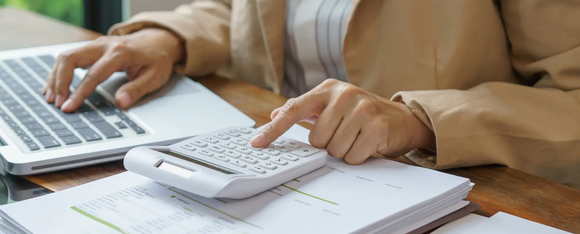 Person using a calculator and laptop while reviewing mortgage refinance options at their desk.
