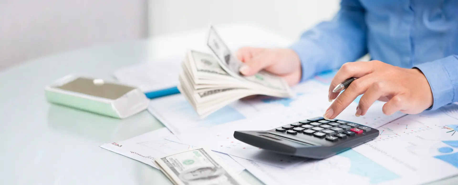 Person counting cash and using a calculator—perfect for first-time home buyers reviewing finances with a mortgage lender.