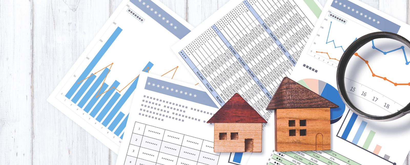 Financial charts and graphs with two wooden house models and a magnifying glass, ideal for first-time home buyers.