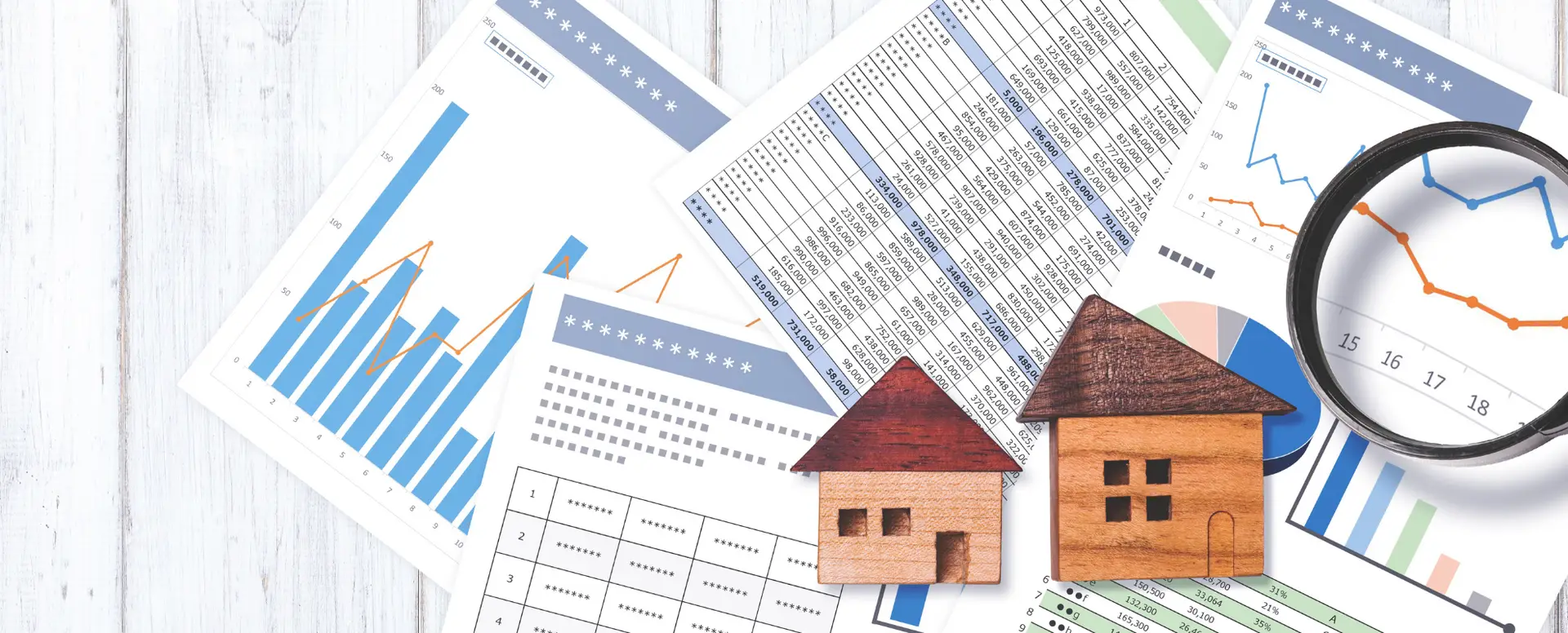 Financial charts and graphs with two wooden house models and a magnifying glass, ideal for first-time home buyers.
