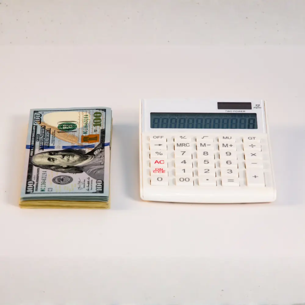 A stack of 100 dollar bills and a calculator—perfect for first-time home buyers planning their mortgage lender options.