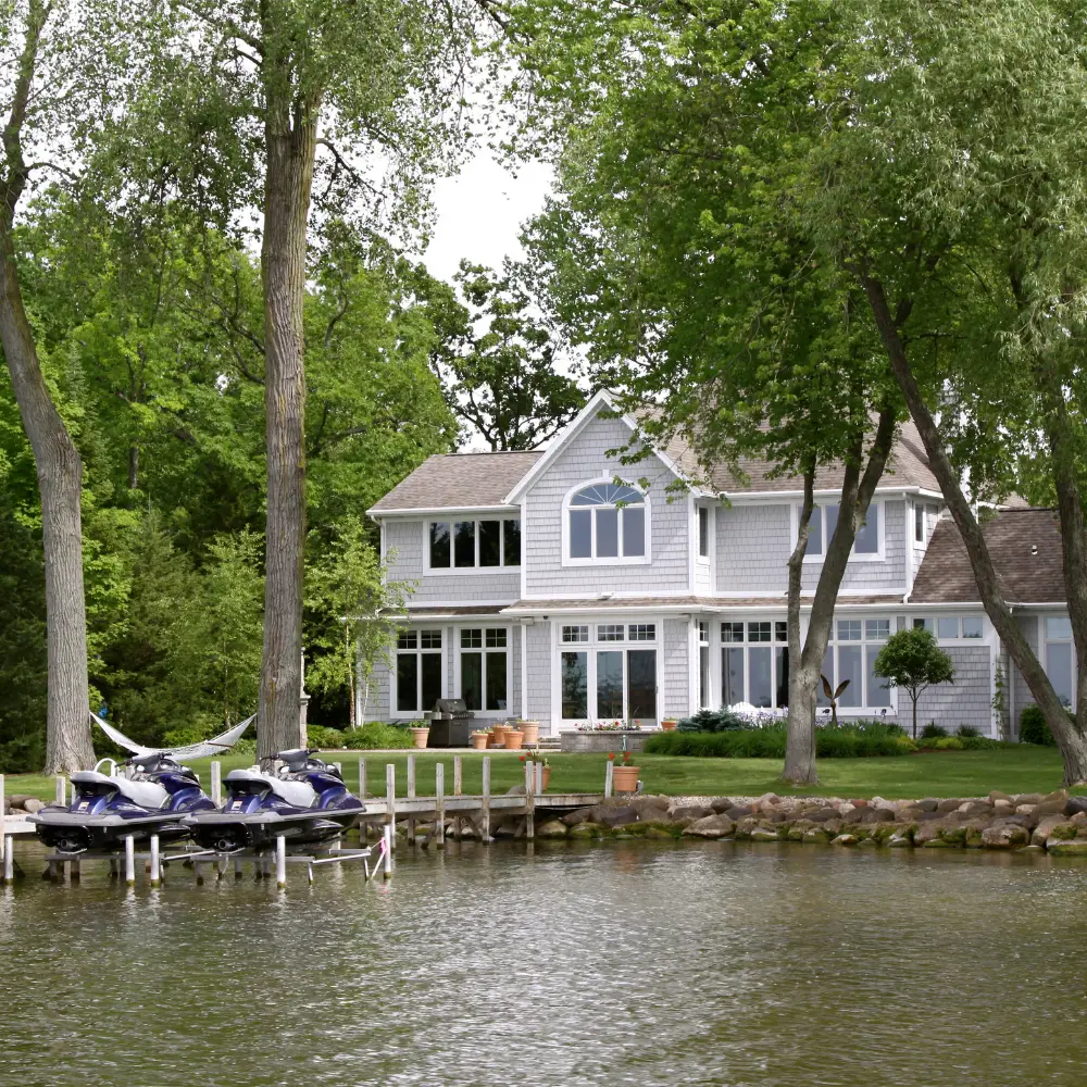 A large lakeside house with a dock, hammock, and jet skis—ask about home loans from your trusted mortgage lender.