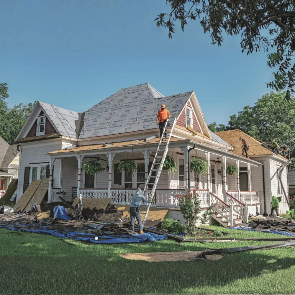Workers repairing the roof of a white house—a common sight for first-time home buyers or after a mortgage refinance.