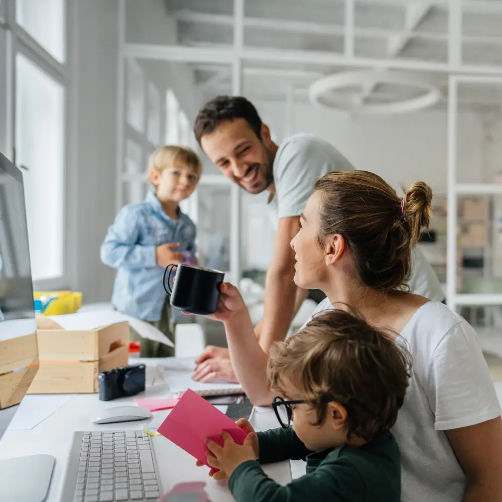 A family of four smiles and talks about mortgage refinance options in a bright, modern home office.